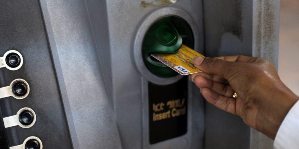 Mano che inserisce una carta di pagamento in uno sportello ATM