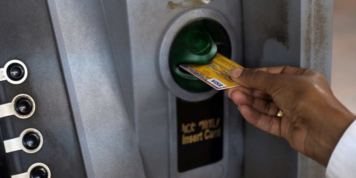 Mano che inserisce una carta di pagamento in uno sportello ATM
