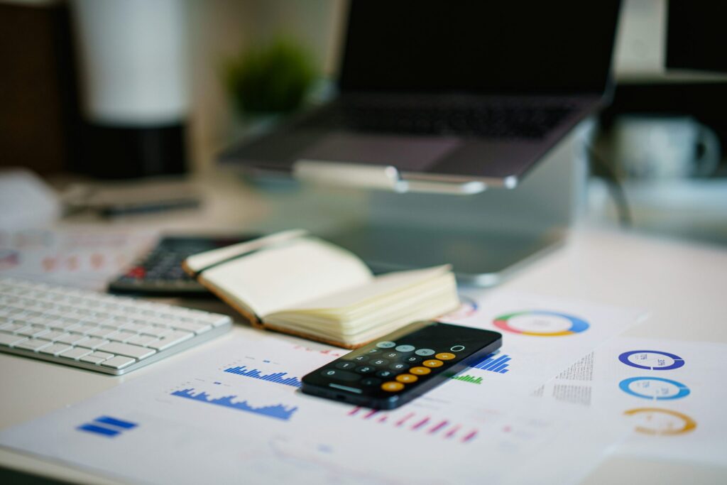 Scrivania con calcolatrice, grafici e computer utilizzati per esaminare dati finanziari